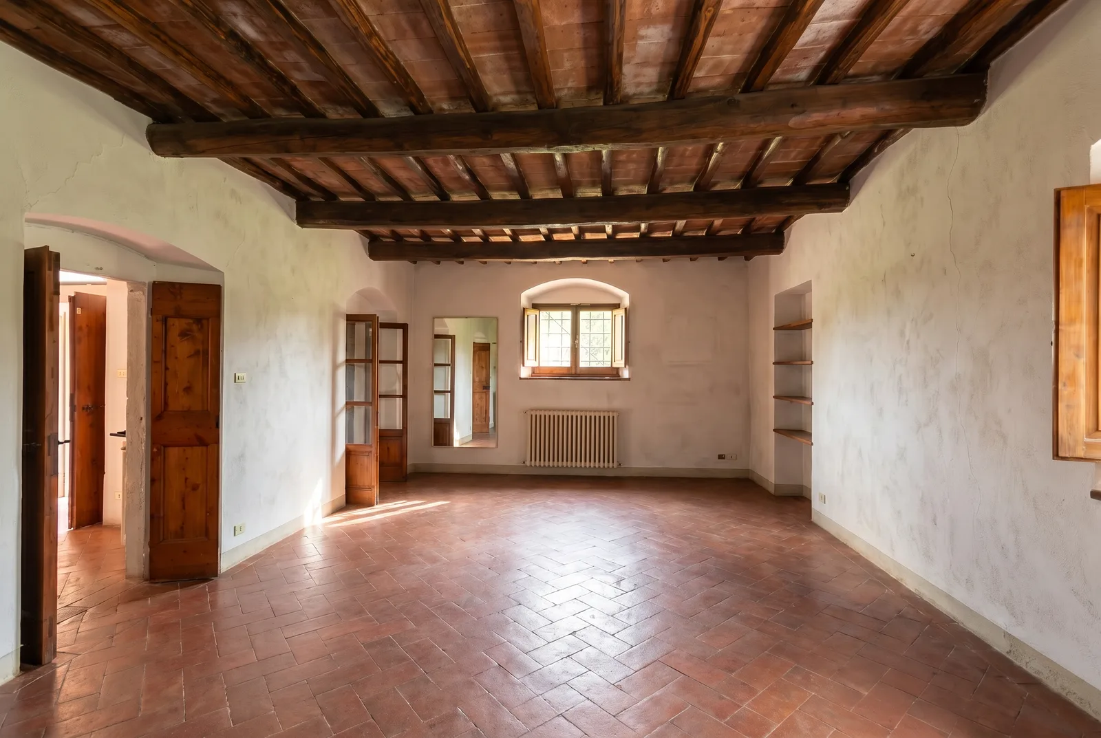Soggiorno con soffitto a travi arredato dal proprietario e lo stesso soggiorno svuotato, col pavimento in cotto a spina: Dopo